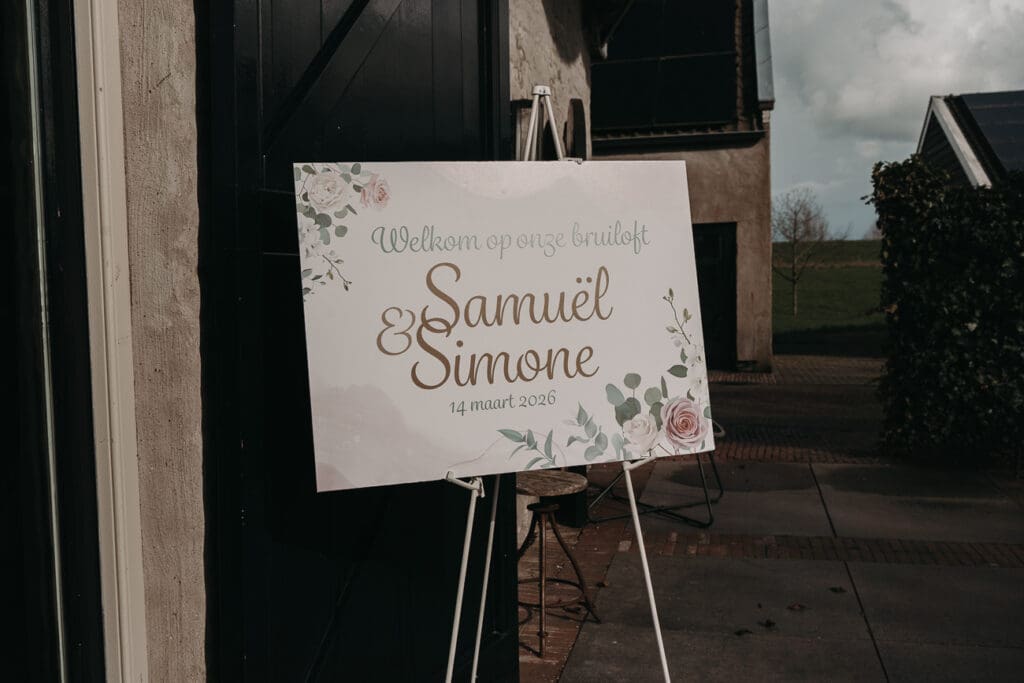 Welkomsbord van het bruidspaar die buiten bij de entree staat