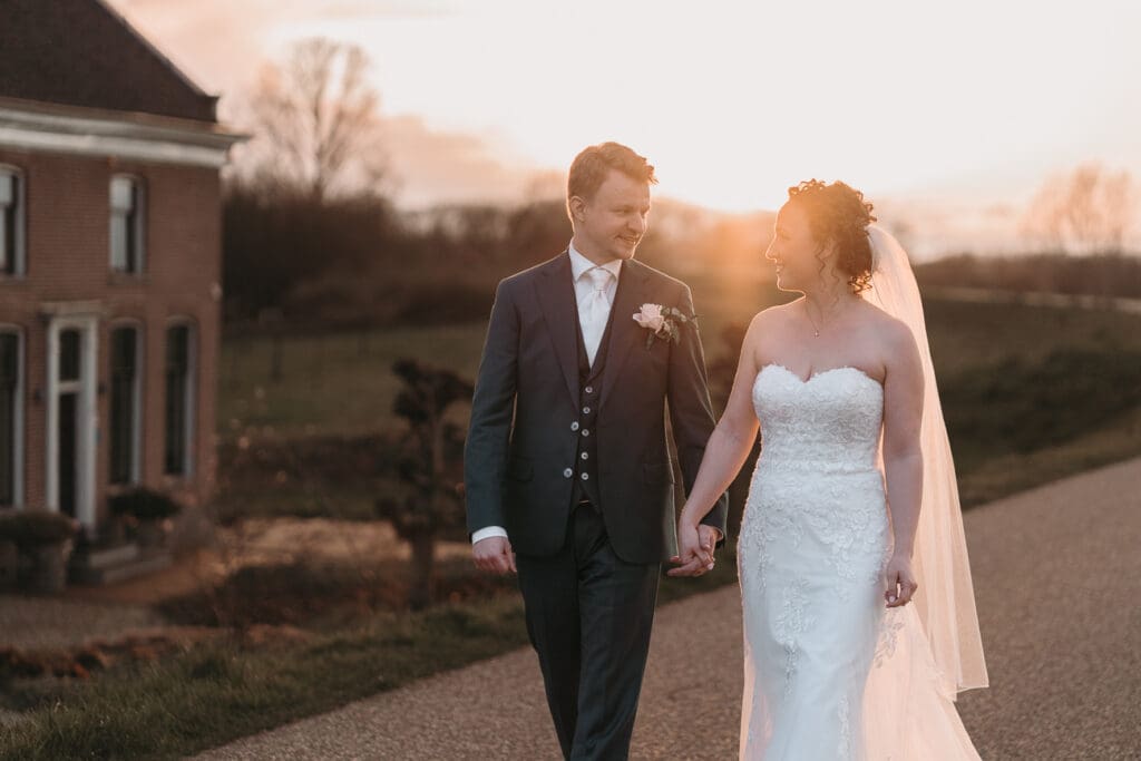 fotoshoot bruidspaar hand in hand tijdens goldenhour 